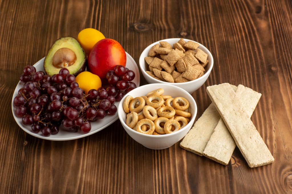 A bowl of fruit, nuts, and crackers on a rustic table, illustrating the best bedtime snacks for diabetics to manage blood sugar.