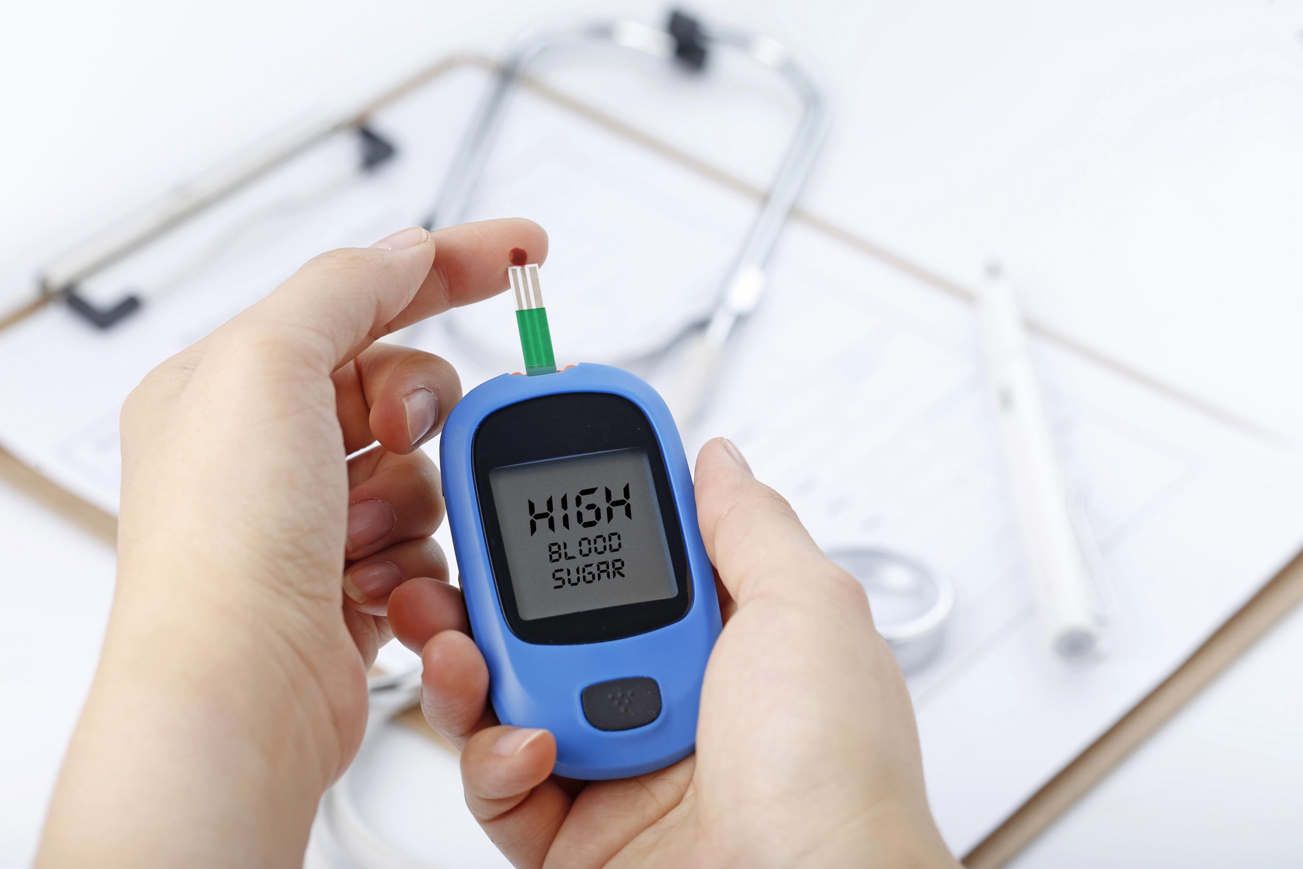 Hand holding a blood glucose meter with stethoscope and chart behind, illustrating the link between high glucose and weight gain.