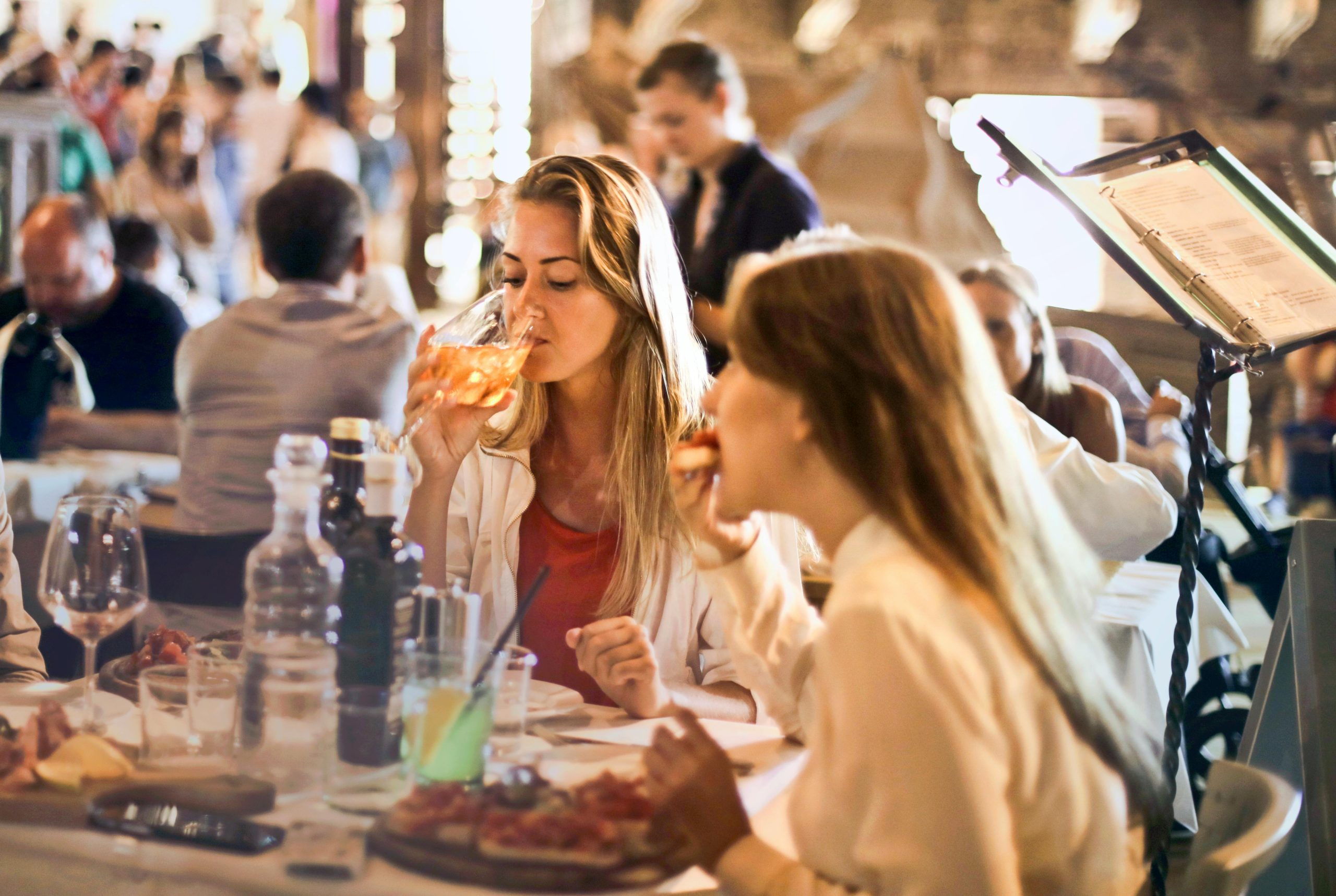 A diverse group enjoying food and drinks at a lively restaurant, illustrating how to eat out safely with diabetes.