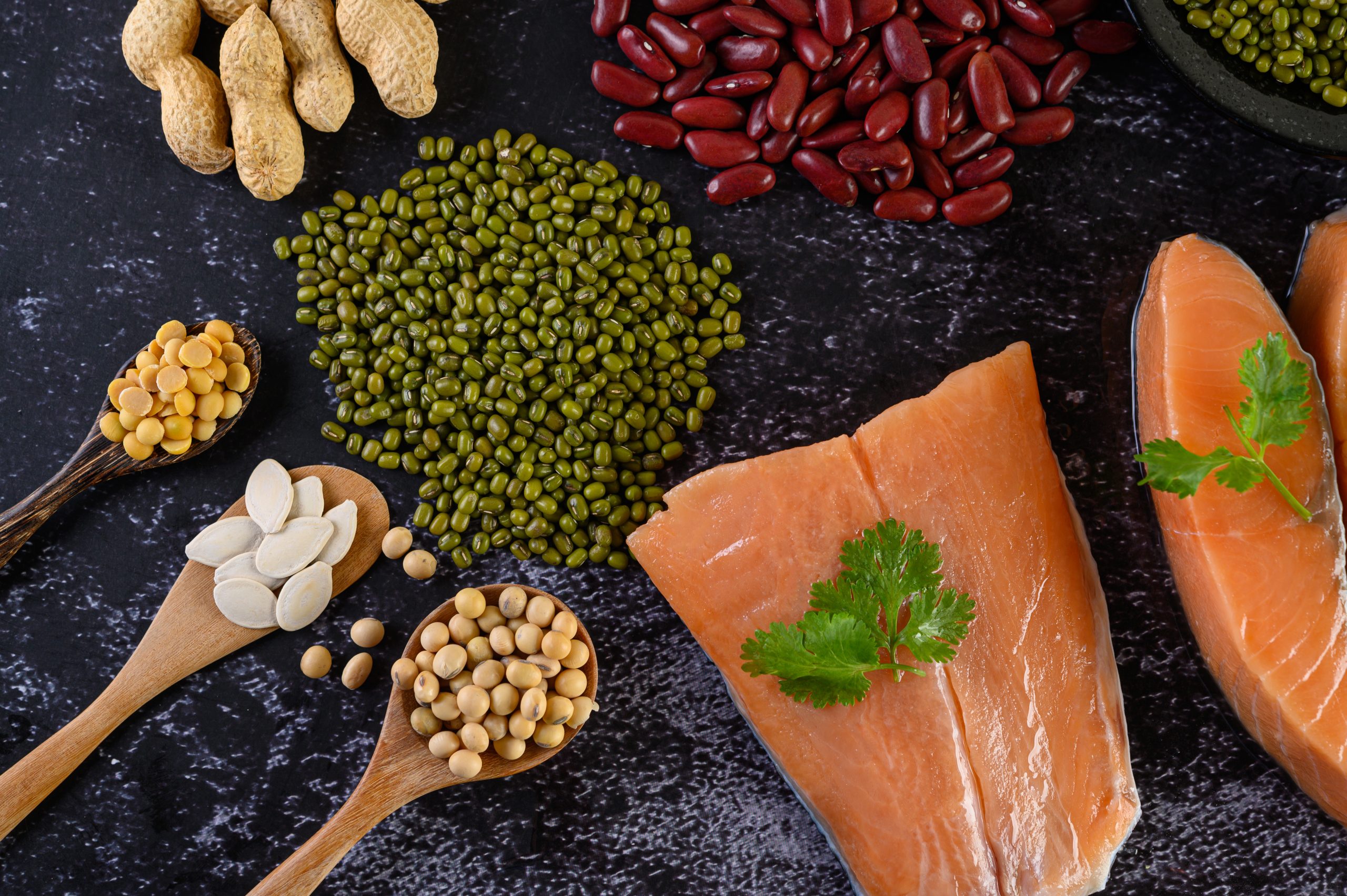 Legumes and salmon on a black surface, illustrating whether a high-protein diet is good for diabetics with benefits and risks.