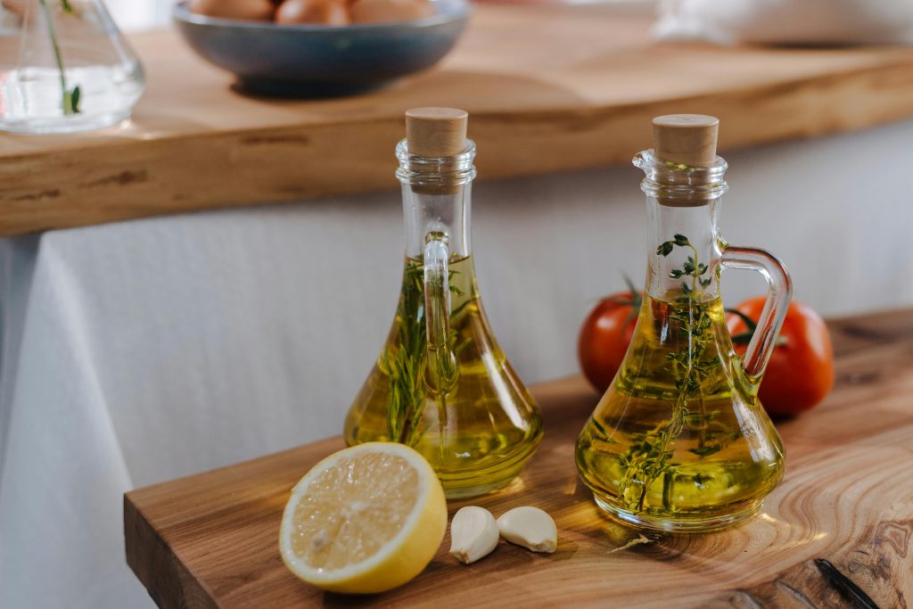 Two olive oil bottles on a wooden cutting board, illustrating top choices in the best cooking oils for diabetics.